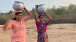 Two women balance large pots on their heads